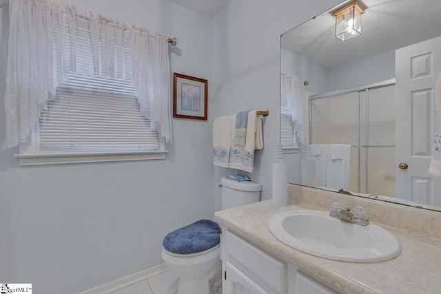 bathroom featuring tile patterned flooring, vanity, toilet, a shower with door, and a textured ceiling