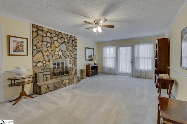 living room featuring ceiling fan, ornamental molding, a textured ceiling, a stone fireplace, and light colored carpet