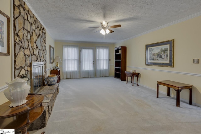 sitting room with ornamental molding, a stone fireplace, and light carpet