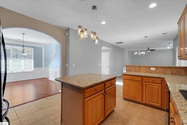 kitchen with light stone counters, hanging light fixtures, and a kitchen island