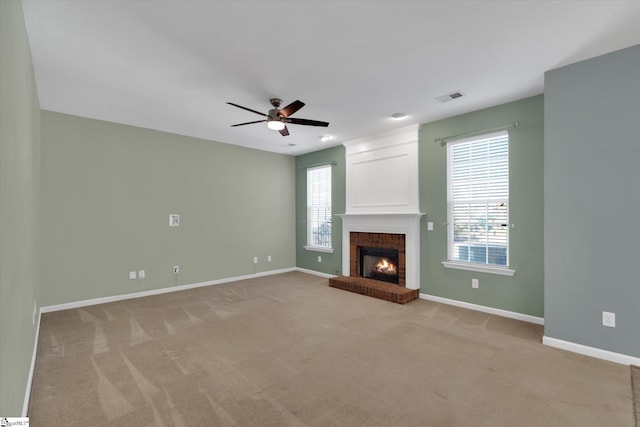 unfurnished living room with ceiling fan, a brick fireplace, and light carpet