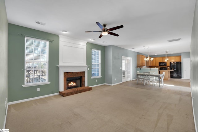 unfurnished living room featuring light carpet, ceiling fan with notable chandelier, and a fireplace