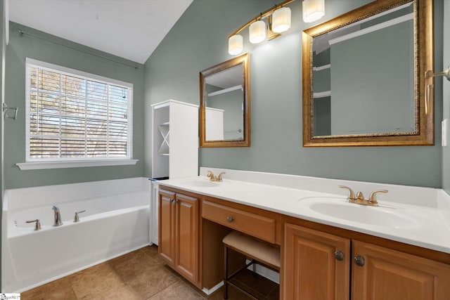 bathroom with tile patterned flooring, vaulted ceiling, a washtub, and vanity