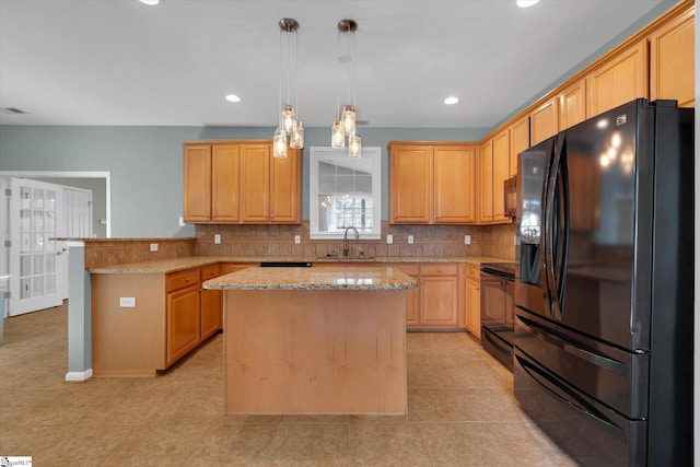 kitchen with pendant lighting, backsplash, a center island, light stone counters, and black appliances