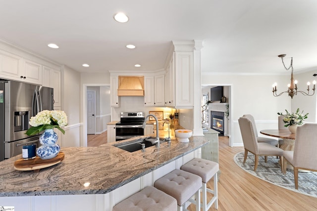 kitchen featuring premium range hood, white cabinetry, ornamental molding, appliances with stainless steel finishes, and stone counters