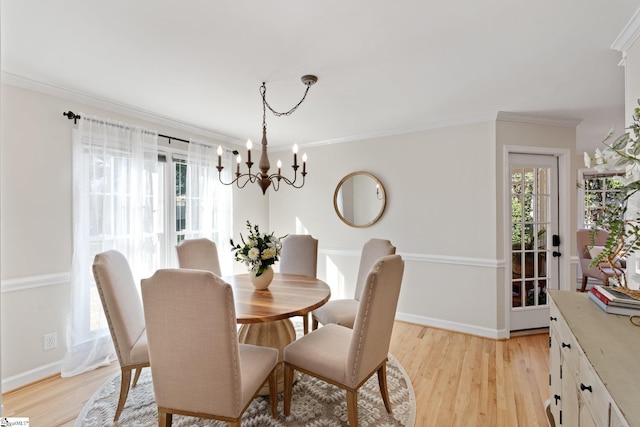 dining area with crown molding, a notable chandelier, and light wood-type flooring