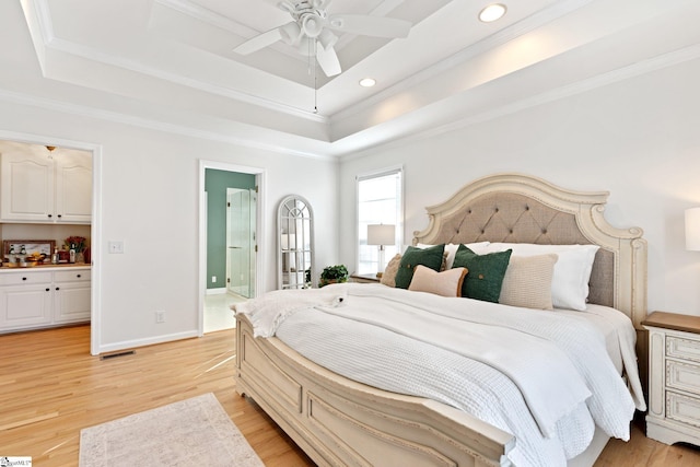 bedroom with a raised ceiling, crown molding, and ensuite bath