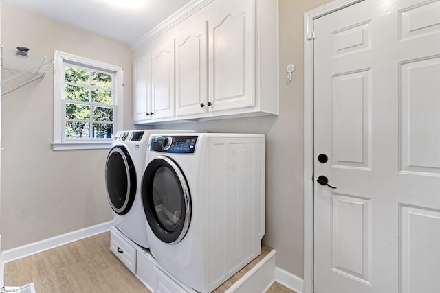 washroom with cabinets, washing machine and dryer, and light wood-type flooring