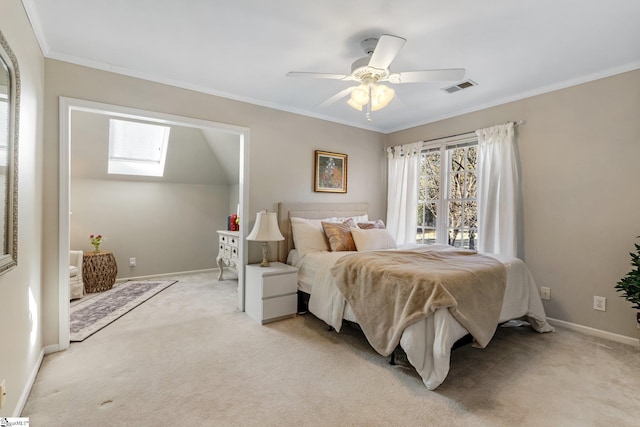 carpeted bedroom with vaulted ceiling with skylight, ornamental molding, and ceiling fan