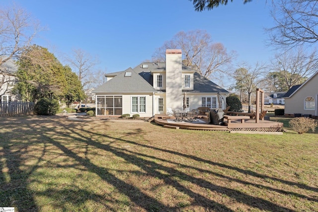 rear view of property with a wooden deck, a yard, and a sunroom