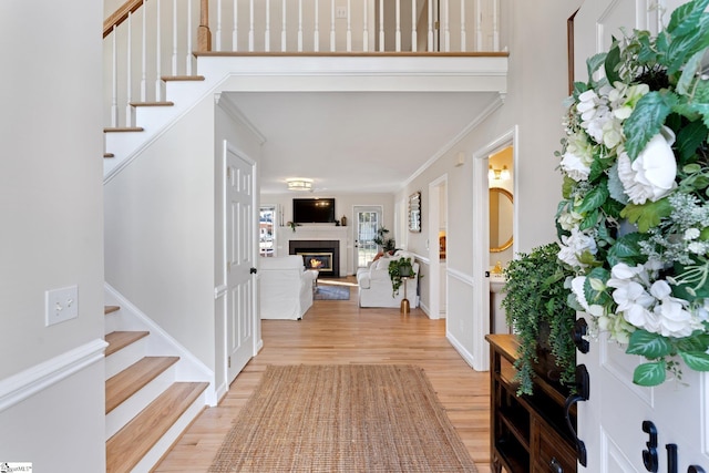 entryway with ornamental molding and light wood-type flooring