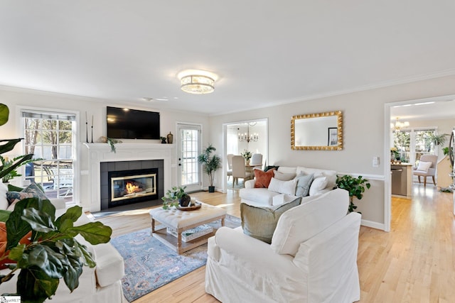 living room with crown molding, an inviting chandelier, and light hardwood / wood-style flooring