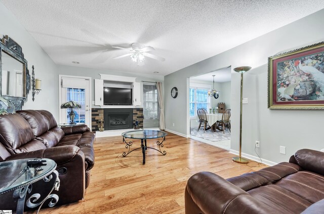 234 Riverrun Dr, Spartanburg, SC 29302 - living room featuring a stone fireplace, wood-type flooring, a textured ceiling, and ceiling fan with notable chandelier