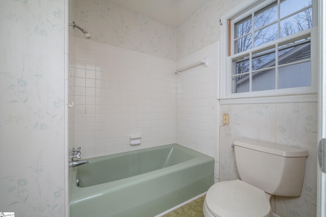 bathroom featuring toilet and tiled shower / bath combo