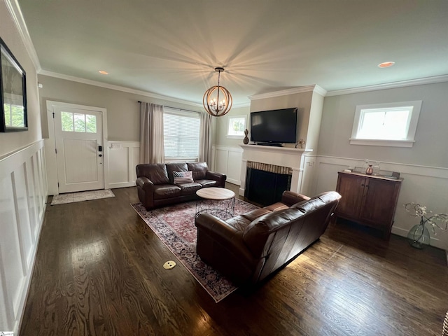 living room featuring ornamental molding, a brick fireplace, dark hardwood / wood-style floors, and an inviting chandelier