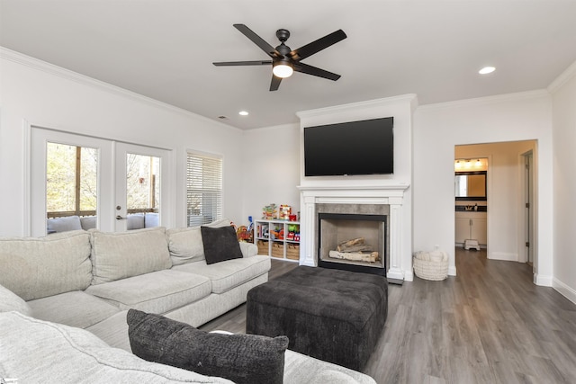 living room with crown molding, ceiling fan, hardwood / wood-style floors, a fireplace, and french doors