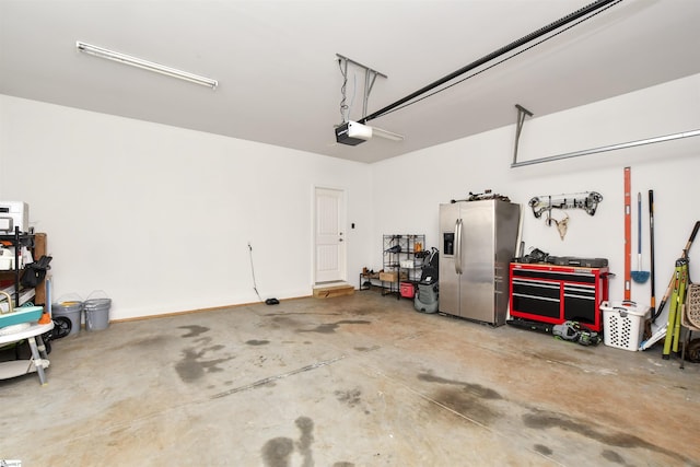 garage with a garage door opener and stainless steel fridge