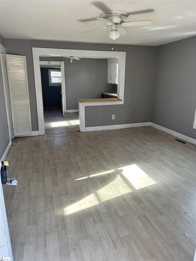 unfurnished living room featuring ceiling fan, a textured ceiling, and light hardwood / wood-style floors