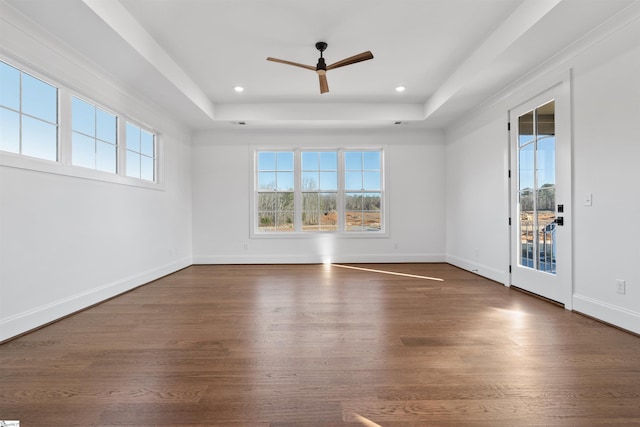 unfurnished room featuring dark hardwood / wood-style floors, ceiling fan, and a tray ceiling