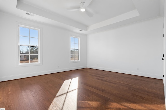 unfurnished room featuring a raised ceiling, ceiling fan, ornamental molding, and dark hardwood / wood-style flooring