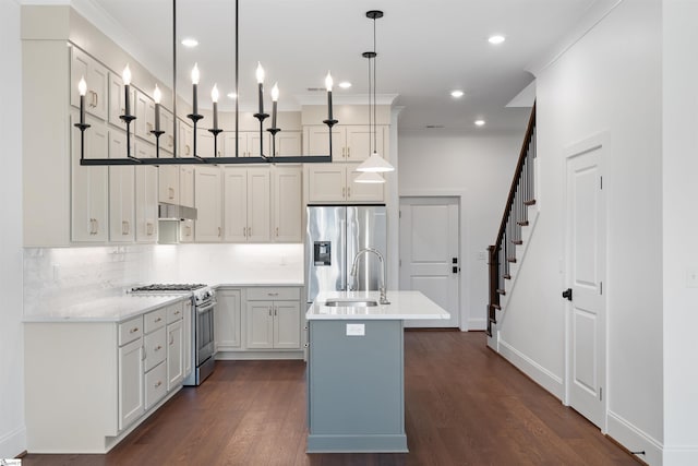 kitchen featuring appliances with stainless steel finishes, pendant lighting, an island with sink, sink, and dark wood-type flooring