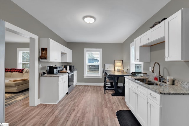 kitchen with white cabinetry, sink, light stone counters, stainless steel appliances, and light hardwood / wood-style flooring