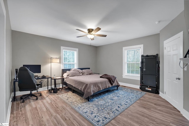 bedroom with multiple windows, wood-type flooring, and ceiling fan