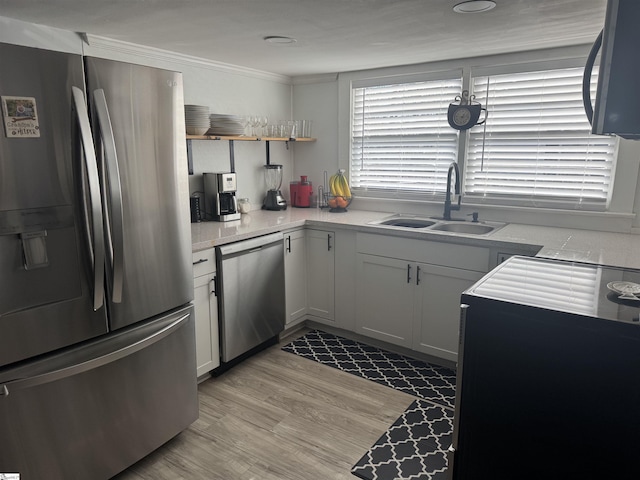 kitchen featuring stainless steel appliances, white cabinetry, sink, and light hardwood / wood-style floors