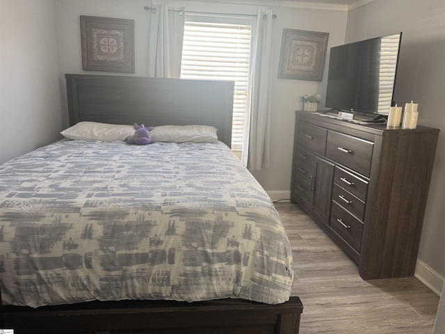 bedroom with ornamental molding and light hardwood / wood-style floors