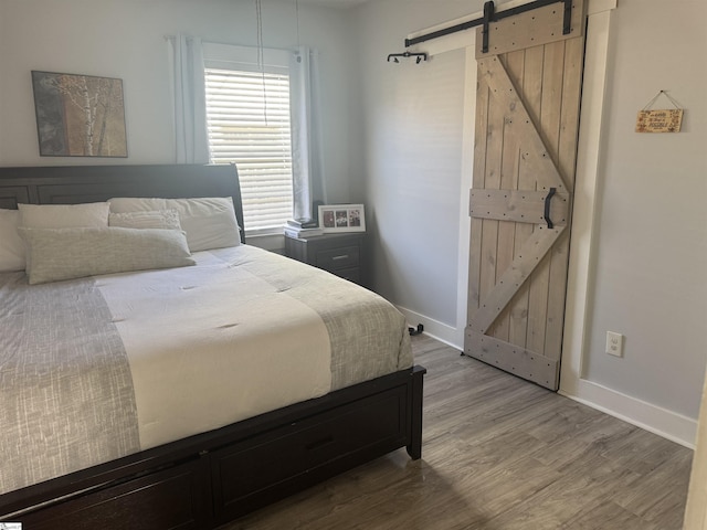 bedroom with a barn door and hardwood / wood-style floors