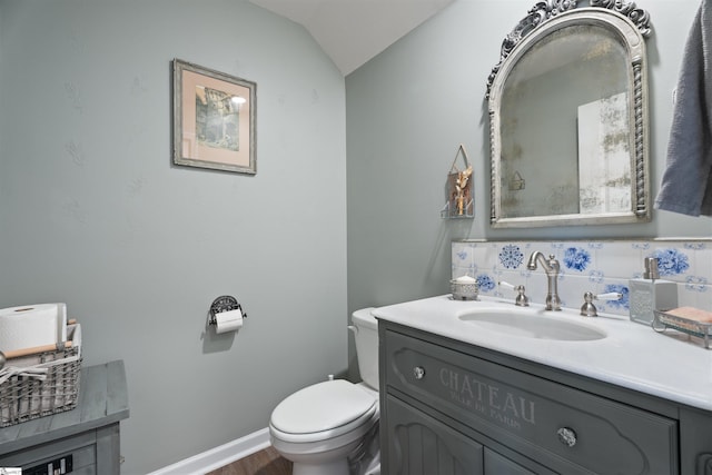 bathroom featuring vaulted ceiling, vanity, backsplash, and toilet