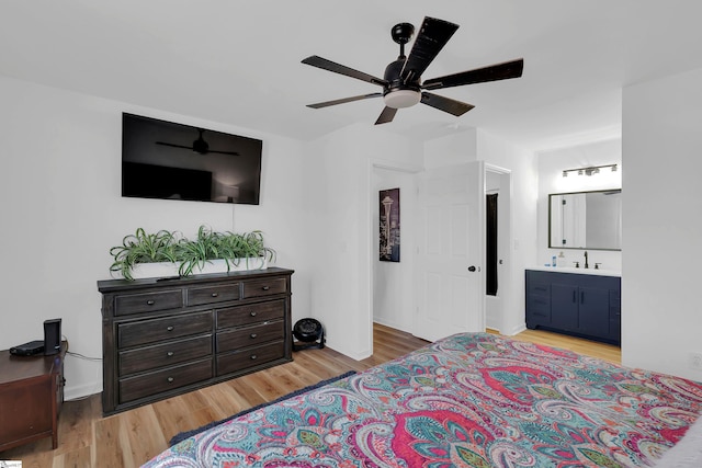 bedroom with ceiling fan, ensuite bathroom, sink, and light hardwood / wood-style floors