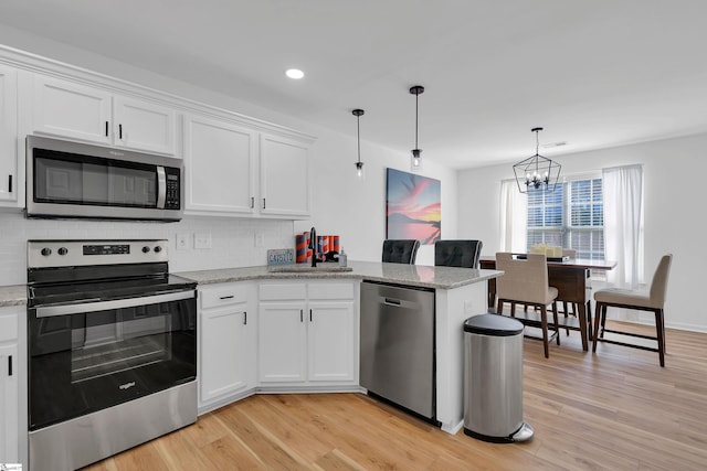 kitchen featuring white cabinetry, appliances with stainless steel finishes, pendant lighting, and backsplash