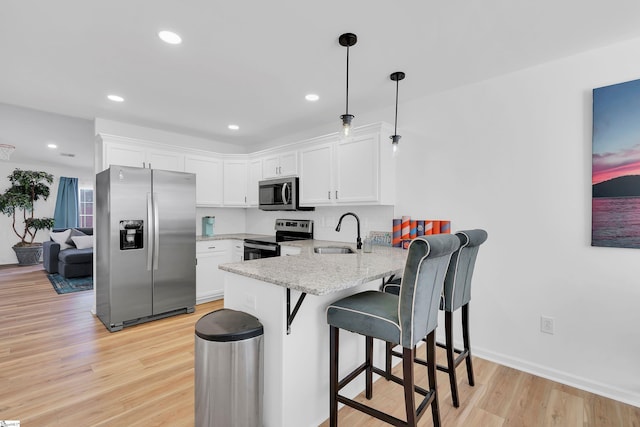 kitchen with sink, kitchen peninsula, pendant lighting, stainless steel appliances, and white cabinets