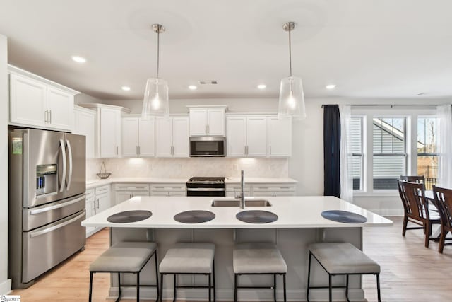 kitchen featuring white cabinetry, appliances with stainless steel finishes, sink, and pendant lighting