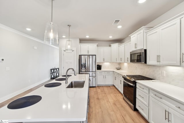 kitchen with sink, white cabinetry, hanging light fixtures, a kitchen island with sink, and stainless steel appliances