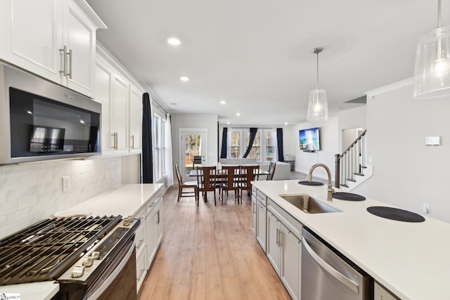 kitchen with pendant lighting, sink, white cabinetry, and stainless steel appliances