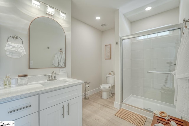 bathroom with wood-type flooring, toilet, an enclosed shower, and vanity