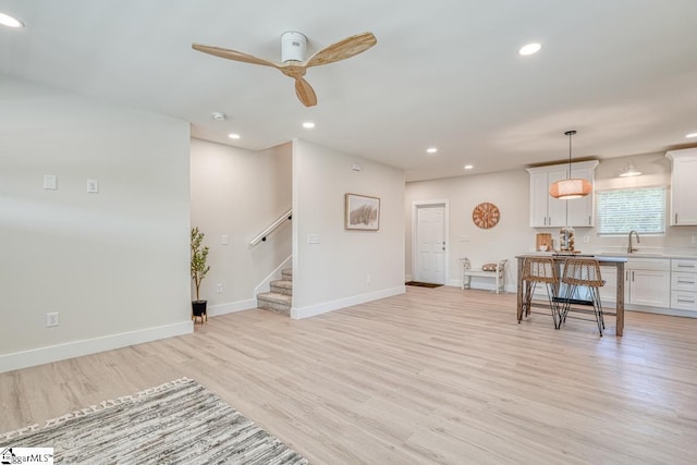 living room featuring ceiling fan, sink, and light hardwood / wood-style flooring