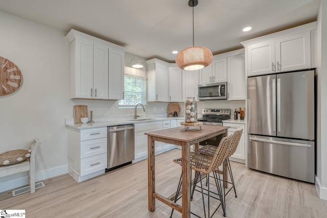 kitchen featuring white cabinetry, appliances with stainless steel finishes, sink, and light wood-type flooring