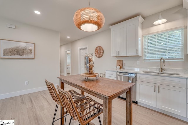 kitchen with pendant lighting, sink, light hardwood / wood-style flooring, dishwasher, and white cabinets