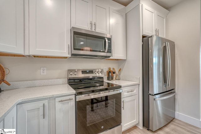 kitchen featuring white cabinetry, stainless steel appliances, light hardwood / wood-style floors, and light stone counters