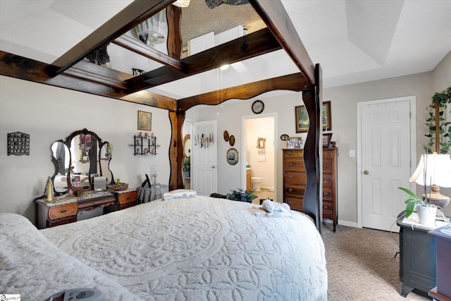 carpeted bedroom featuring a tray ceiling and connected bathroom