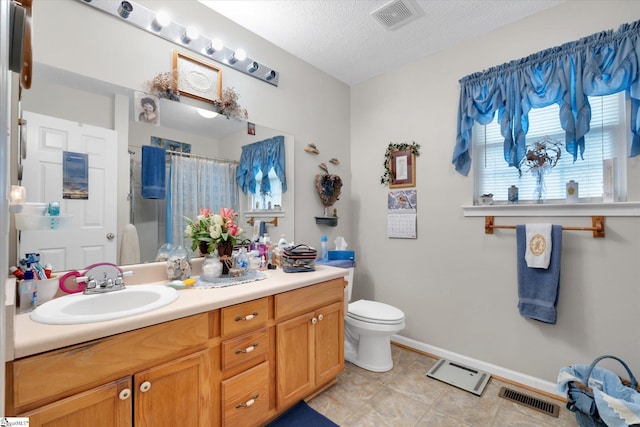 bathroom with walk in shower, vanity, toilet, and a textured ceiling