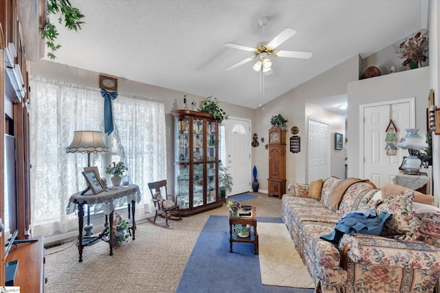 living room with ceiling fan, vaulted ceiling, light carpet, and a textured ceiling