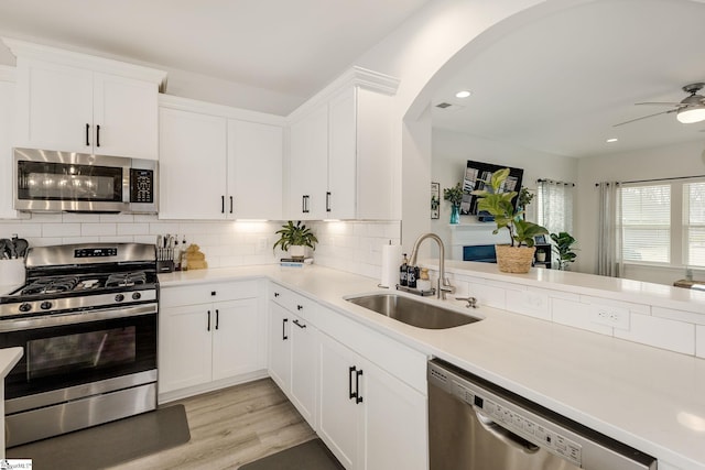 kitchen with sink, white cabinets, backsplash, light hardwood / wood-style floors, and stainless steel appliances