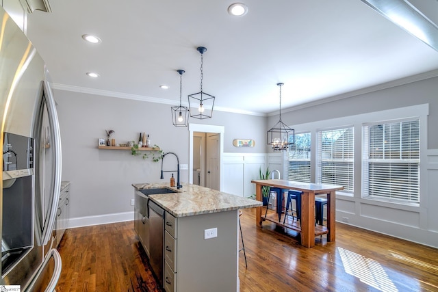 kitchen featuring pendant lighting, crown molding, appliances with stainless steel finishes, dark hardwood / wood-style floors, and a center island with sink