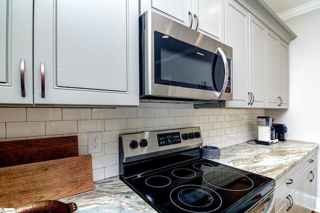 kitchen with crown molding, appliances with stainless steel finishes, backsplash, light stone counters, and white cabinets