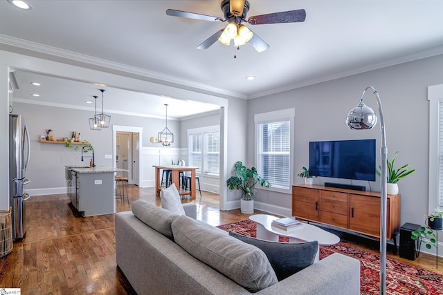 living room featuring ornamental molding, sink, ceiling fan with notable chandelier, and dark hardwood / wood-style flooring