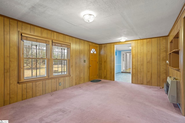 spare room with heating unit, a textured ceiling, and carpet flooring